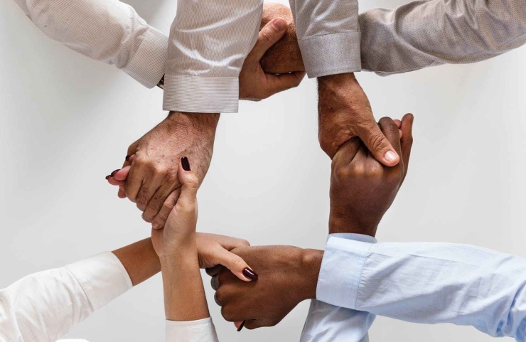 photo of four persons uniting hands